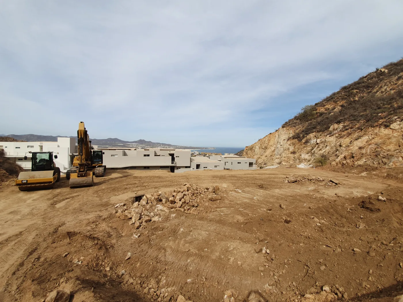Earthmoving equipment and a cleared construction area above existing condos