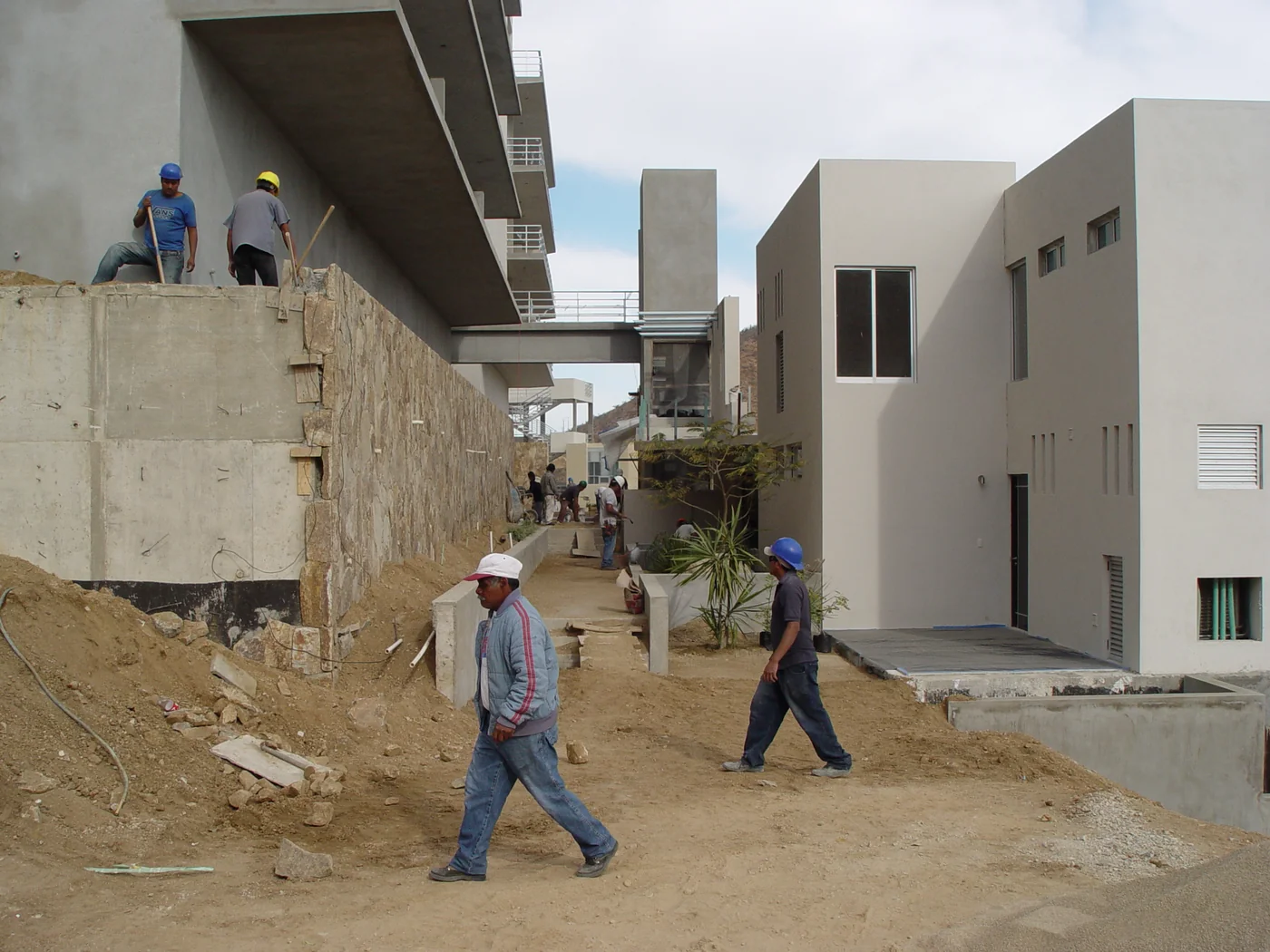 Construction crews working on walkways and stone walls between residences