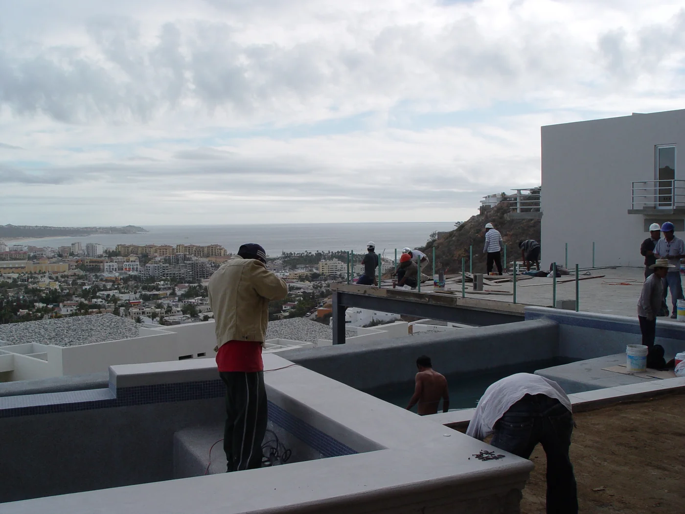 Workers finishing a pool and terrace overlooking Cabo San Lucas