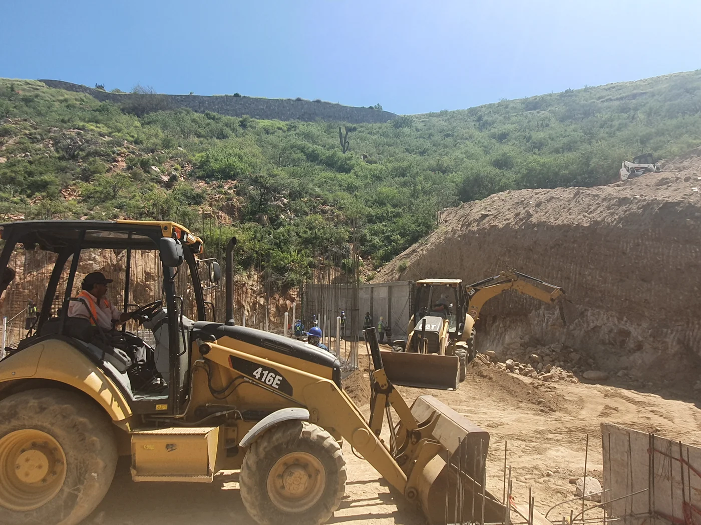Excavators preparing the hillside beside foundations and reinforcing steel