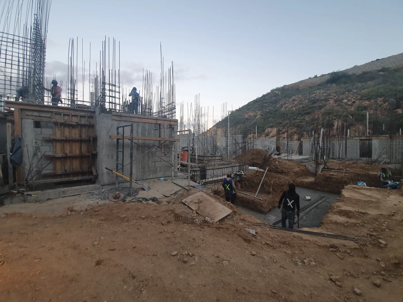 Construction crews working among concrete walls and reinforcing steel