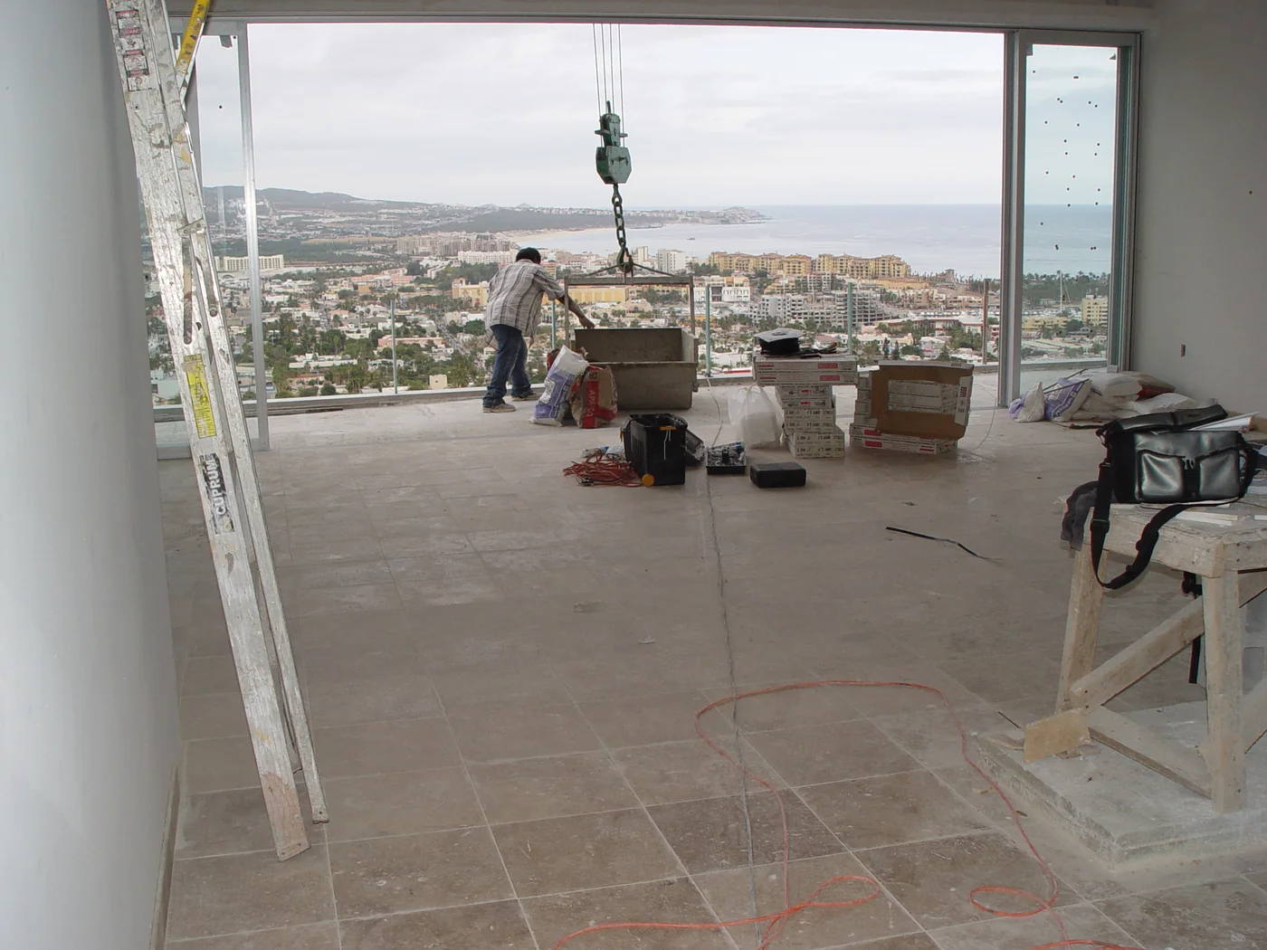 Building materials being lifted into a condo with views toward Cabo San Lucas bay